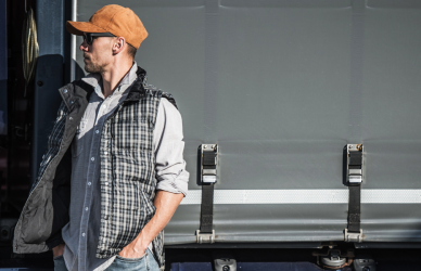 man in hat standing in front of semi truck