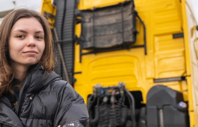 woman standing in front of yellow semi truck