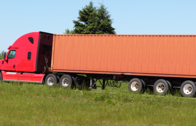 red semi truck with orange trailer on road