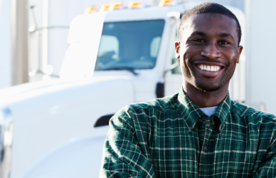smiling black man standing in front of semi truck