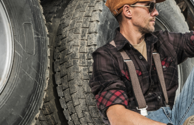 trucker leaning up against semi truck wheels