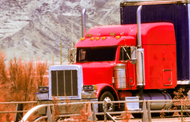 red semi truck on road with mountain in background