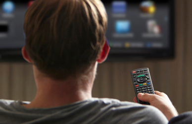 man holding tv remote with tv in background