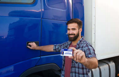 man next to semi truck holding up cdl