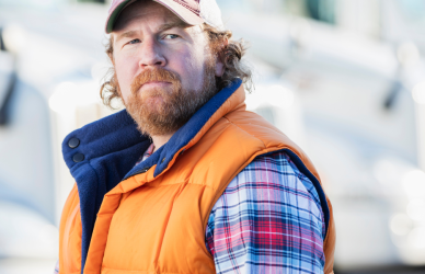 Man in orange vest standing in front of semi trucks