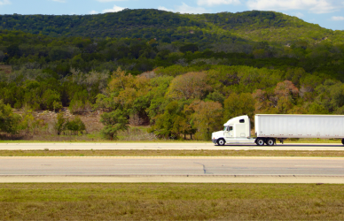 white semi truck on road with green rolling hills in background