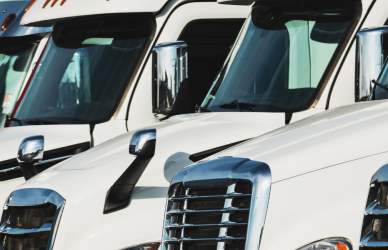 line of white semi trucks parked in lot