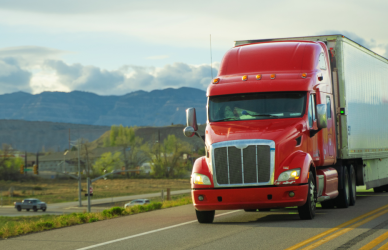 red semi truck on road with mountains in background