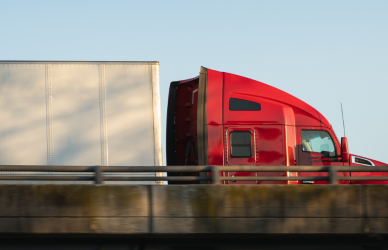 red semi truck with white trailer on bridge