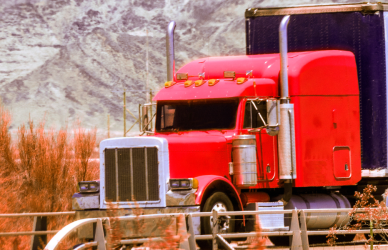 red semi truck with white trailer on road with mountains in background