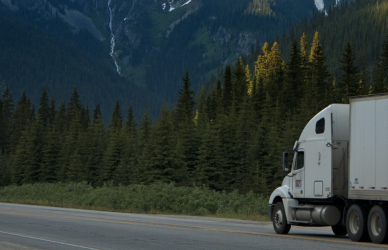 semi truck driving on road with mountain in background