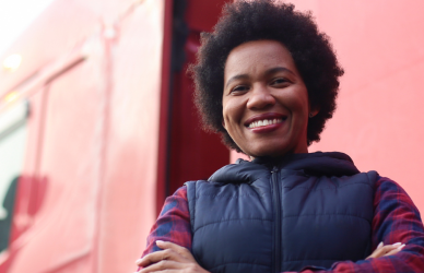 black woman standing in front of red semi truck