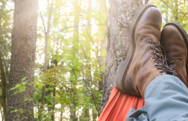 man wearing work boots relaxing in hammock in woods