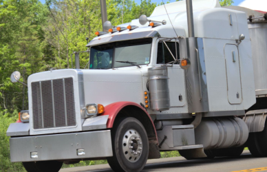 semi truck on road surrounded by green trees