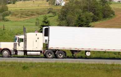 semi truck on road with fields in background
