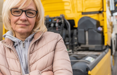woman standing in front of yellow semi truck
