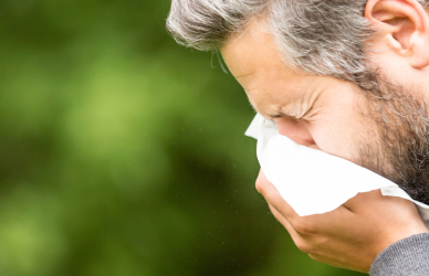 man sneezing into tissue