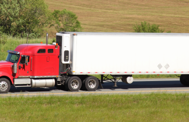 red semi truck with white trailer on road