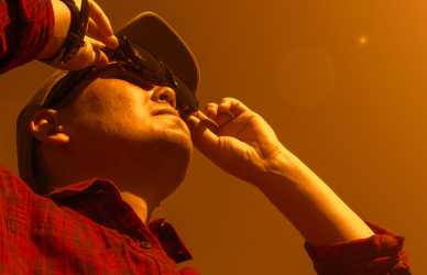 man looking into sun during solar eclipse with glasses