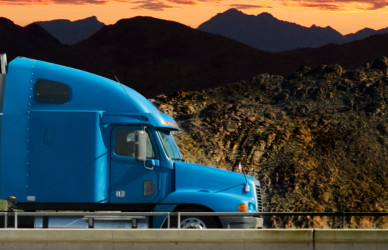 Semi truck crossing bridge with mountains and sunset in background