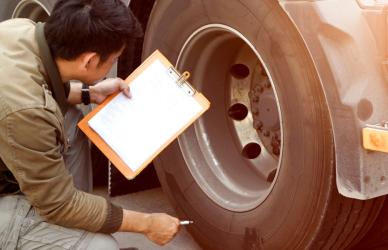 man with clipboard near semi truck tires