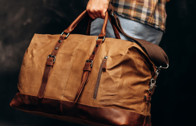 man in jeans and flannel shirt carrying small duffel bag