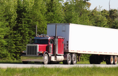 red semi truck pulling white trailer on road