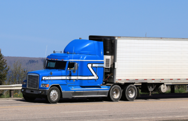 blue semi truck with white trailer on scenic road