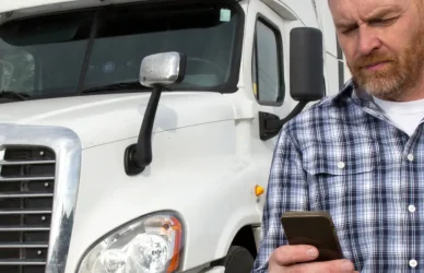 Man looking at phone with semi truck in background