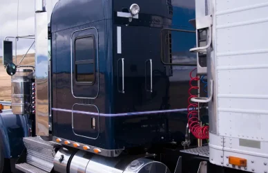 black semi truck pulling white semi on road