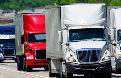 several semi trucks of varying types driving on highway