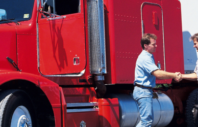 men shaking hands with red semi truck in background