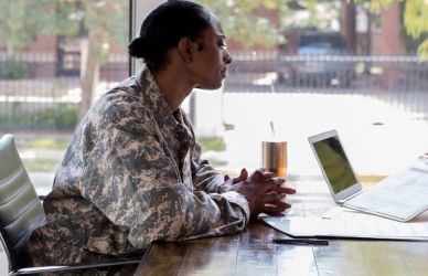 woman in military uniform talking with another woman with laptop