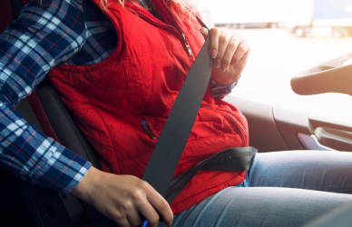 woman truck driver fastening seat belt in semi truck cab