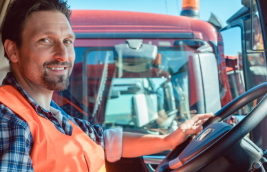 man in safety vest in cab of semi truck