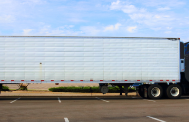 blue semi truck with white trailer in parking lot