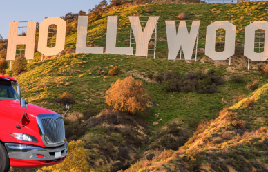 red semi truck in front of hollywood sign