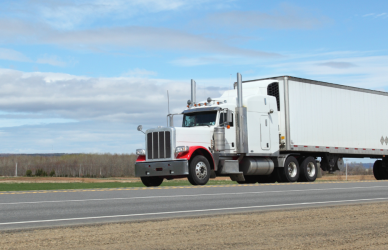 white semi truck pulling white trailer on road