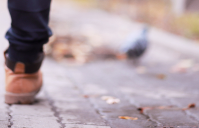 man in workboots walking on cobblestone path