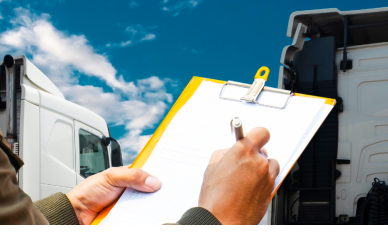 man holding clipboard and pen with semi truck in background