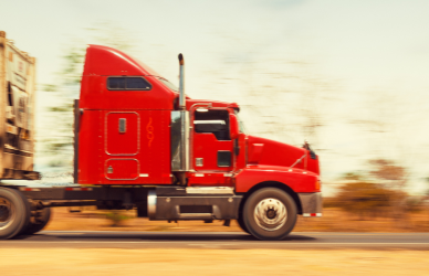 red semi truck pulling white trailer in desert landscape