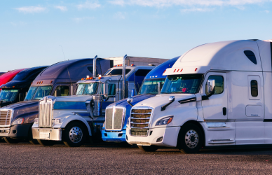 semi trucks of varying types parked in a line in a parking lot