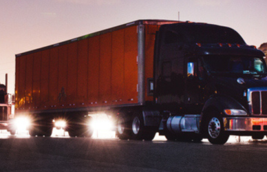 several semi trucks on the road at dusk