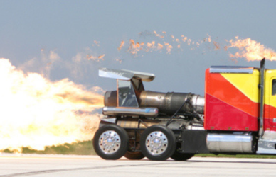 red and yellow semi truck drag racing with flames coming out the back and stacks