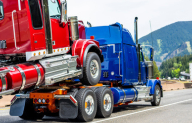 blue semi truck towing red semi truck