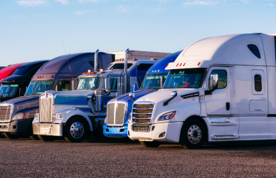 line of various types of semi trucks parked in a row