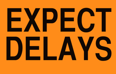 yellow sign with black lettering reading expect delays