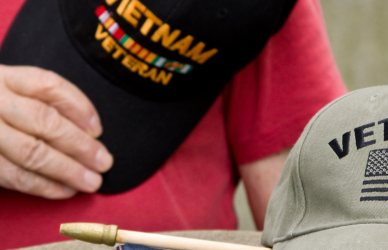 man holding veteran hat with another veteran hat in the foreground