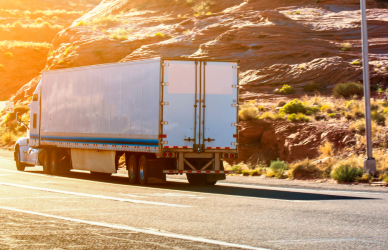 semi truck heading down curving road at sunset