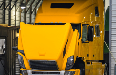 yellow semi truck in garage with hood up
